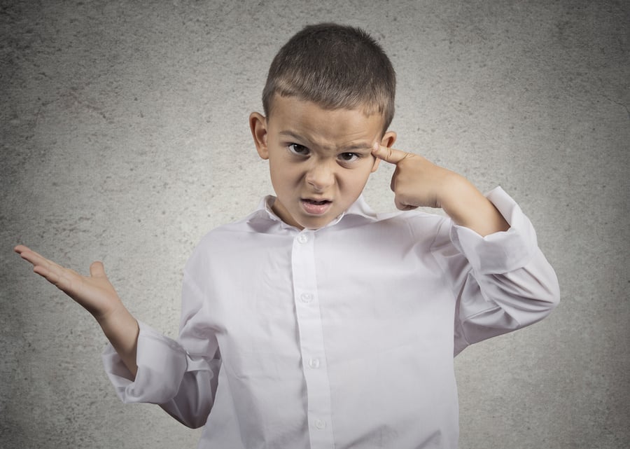 Closeup portrait angry mad child boy gesturing with his finger against temple asking are you crazy? Isolated grey wall background. Negative human emotions facial expression feeling body language